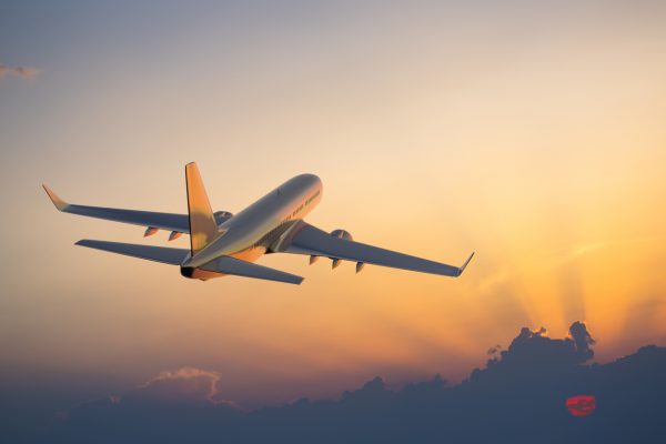 Passenger airplane flying above clouds during sunset wound holidays