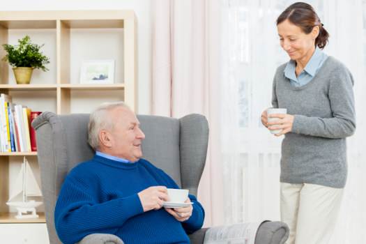 Carer and man having coffee in home
